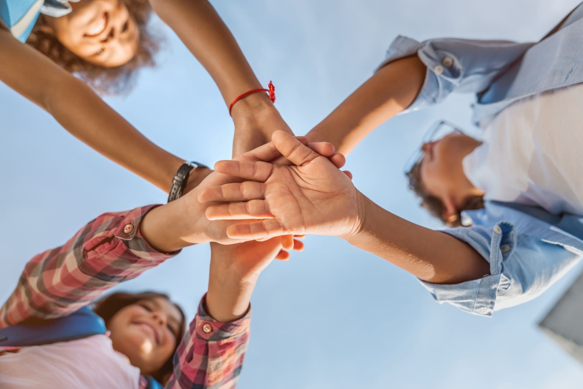 Grupo de personas uniendo sus manos en círculo, simbolizando el liderazgo y la gestión de redes de apoyo, habilidades de un trabajador social fundamentales para el impacto social.