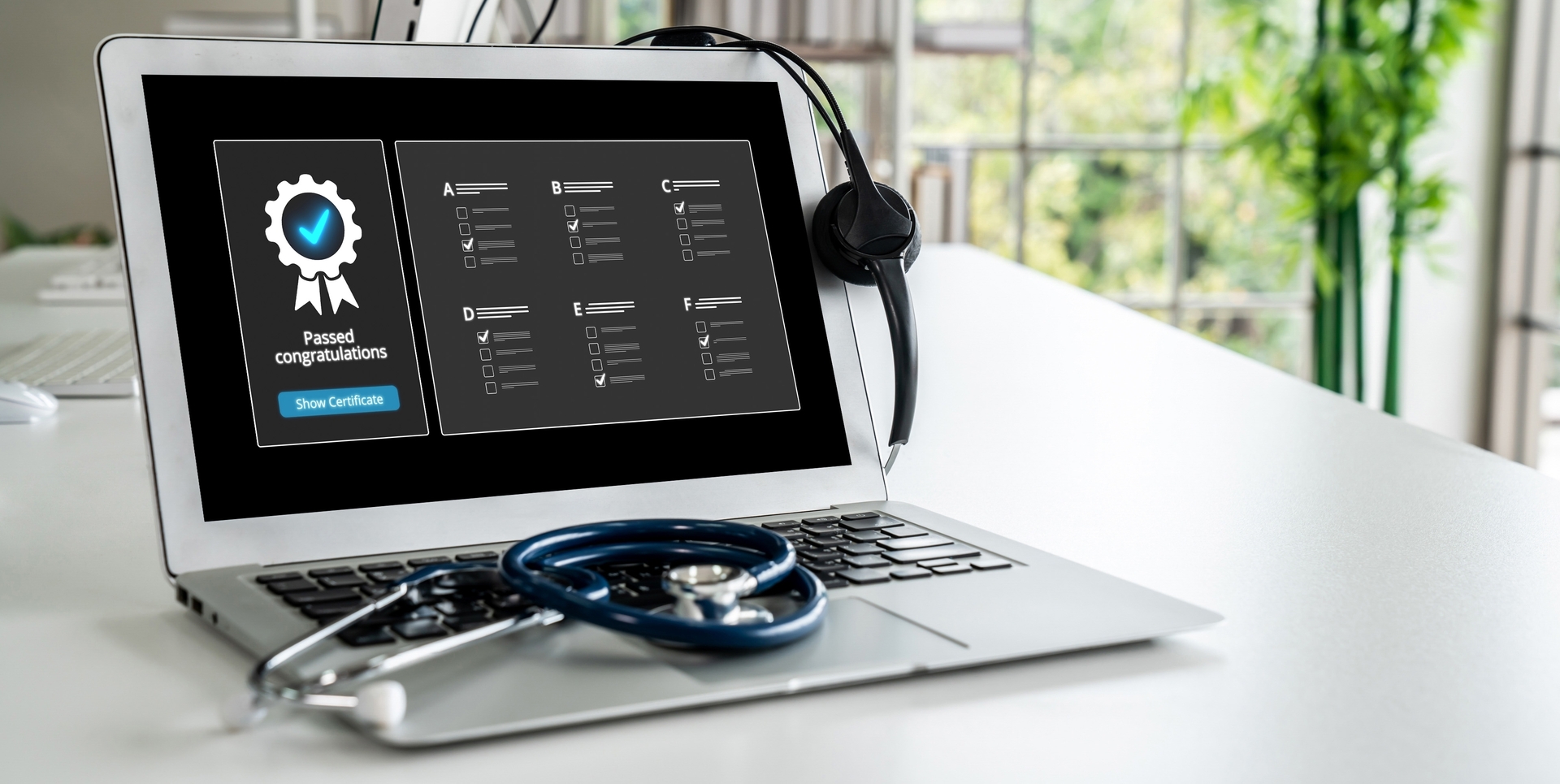 Laptop con certificado de aprobación en pantalla y estetoscopio, representando la especialización en calidad de la salud virtual y educación médica continua.