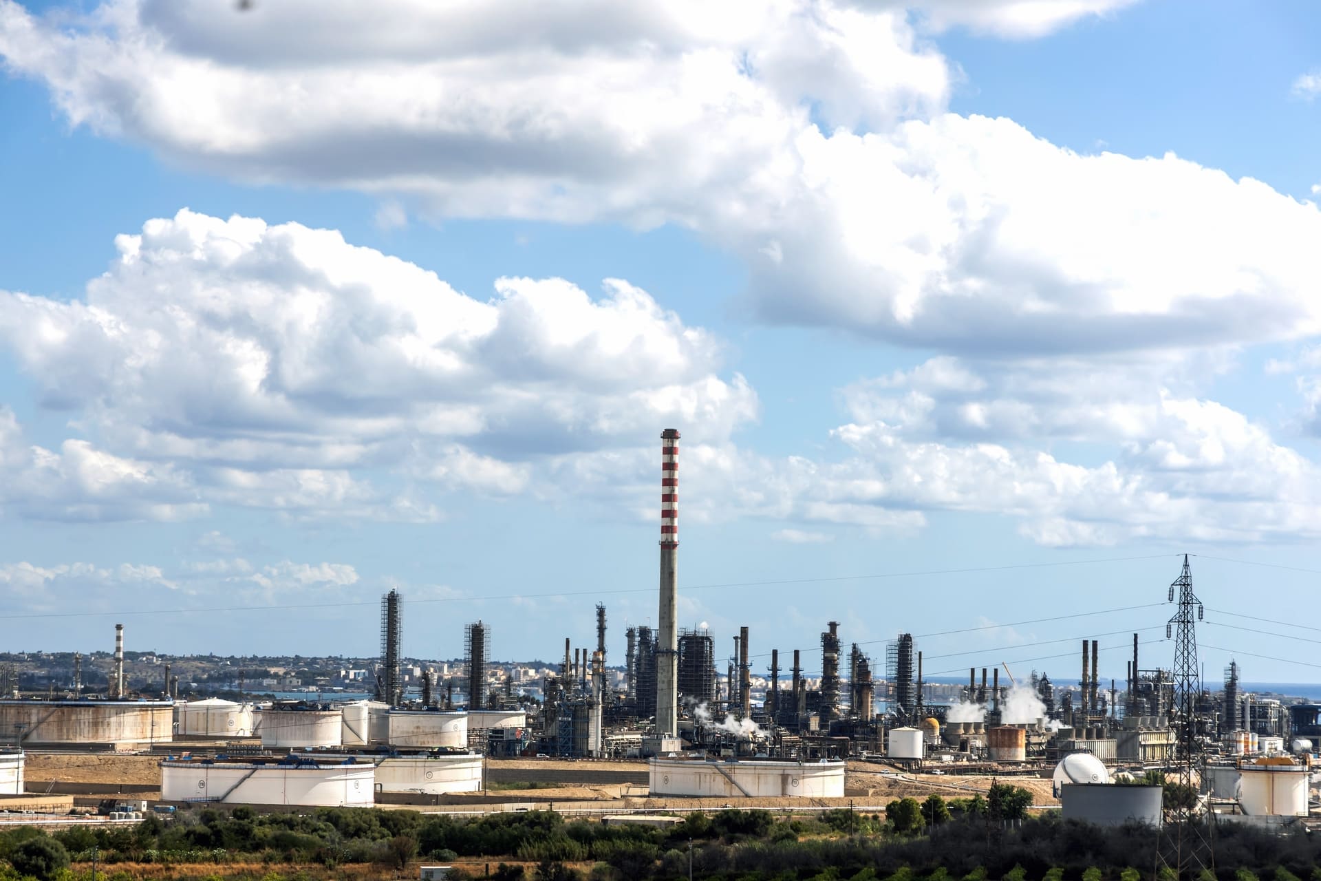 Complejo de planta de producción industrial con torres y tanques de almacenamiento, representando las áreas de la ingeniería industrial dedicadas a la gestión de operaciones y logística a gran escala.